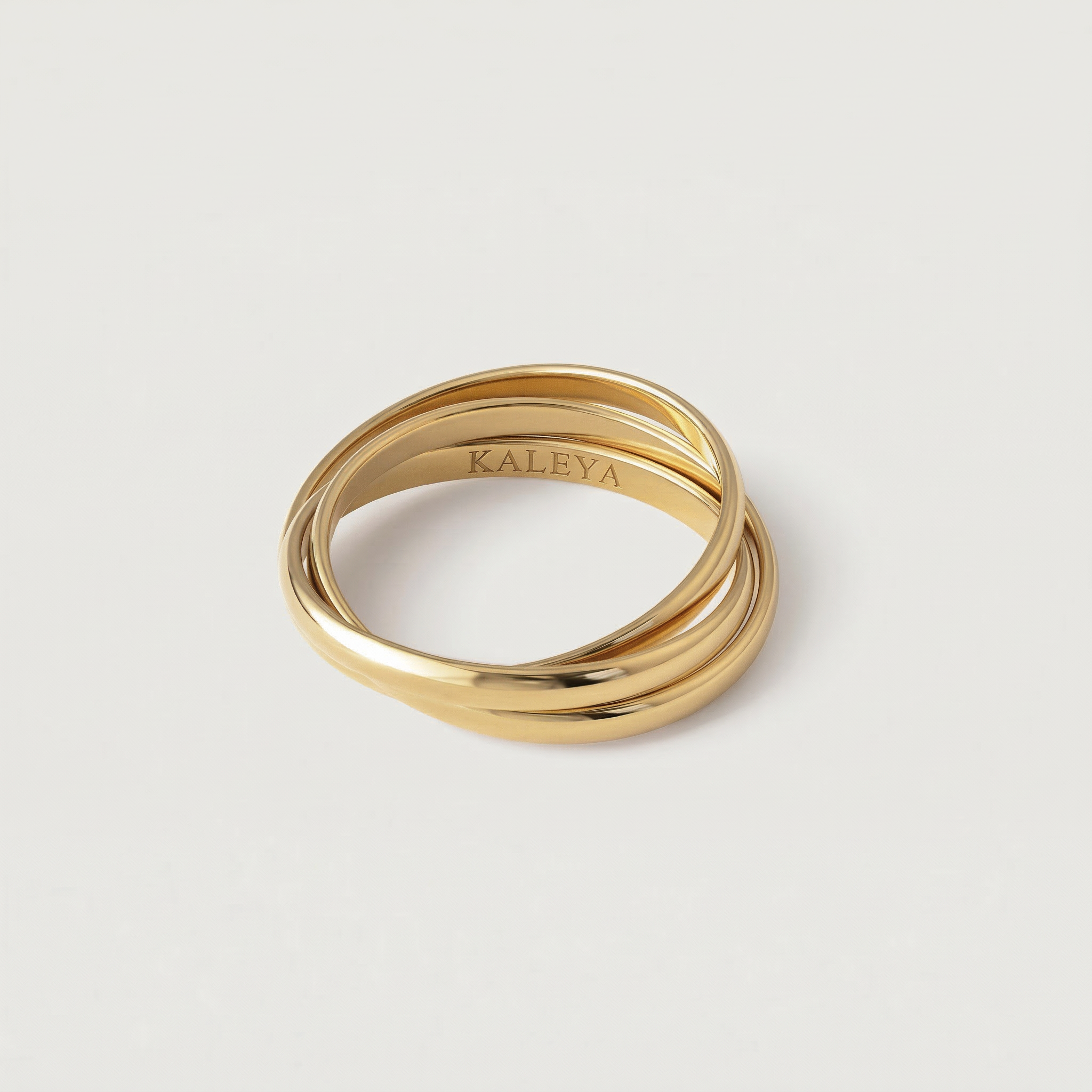 Three gold rings stacked on a light gray background with 'KALEYA' branding.