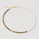 multi gemstone and pearl beaded necklace in gold, with one half strung with imitation pearl rice beads and the other half with faceted mixed quartz beads in green, sage, olive and warm brown tones, joined by a gold accent bead.