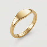 A gold signet ring with a smooth, curved surface on a white background.
