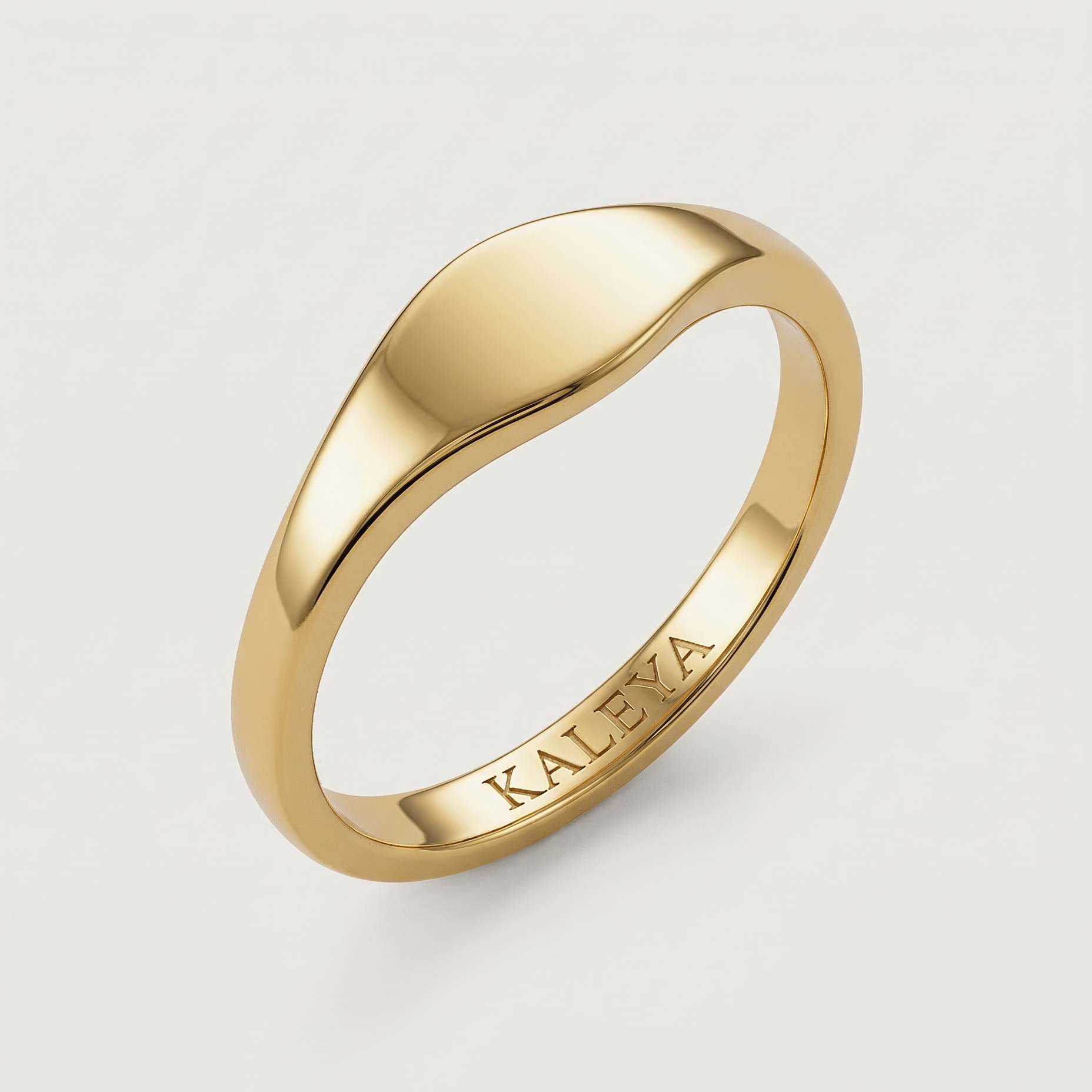 A gold signet ring with a smooth, curved surface on a white background.