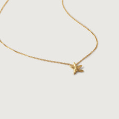 A gold-plated necklace with a small starfish pendant on a twisted chain.