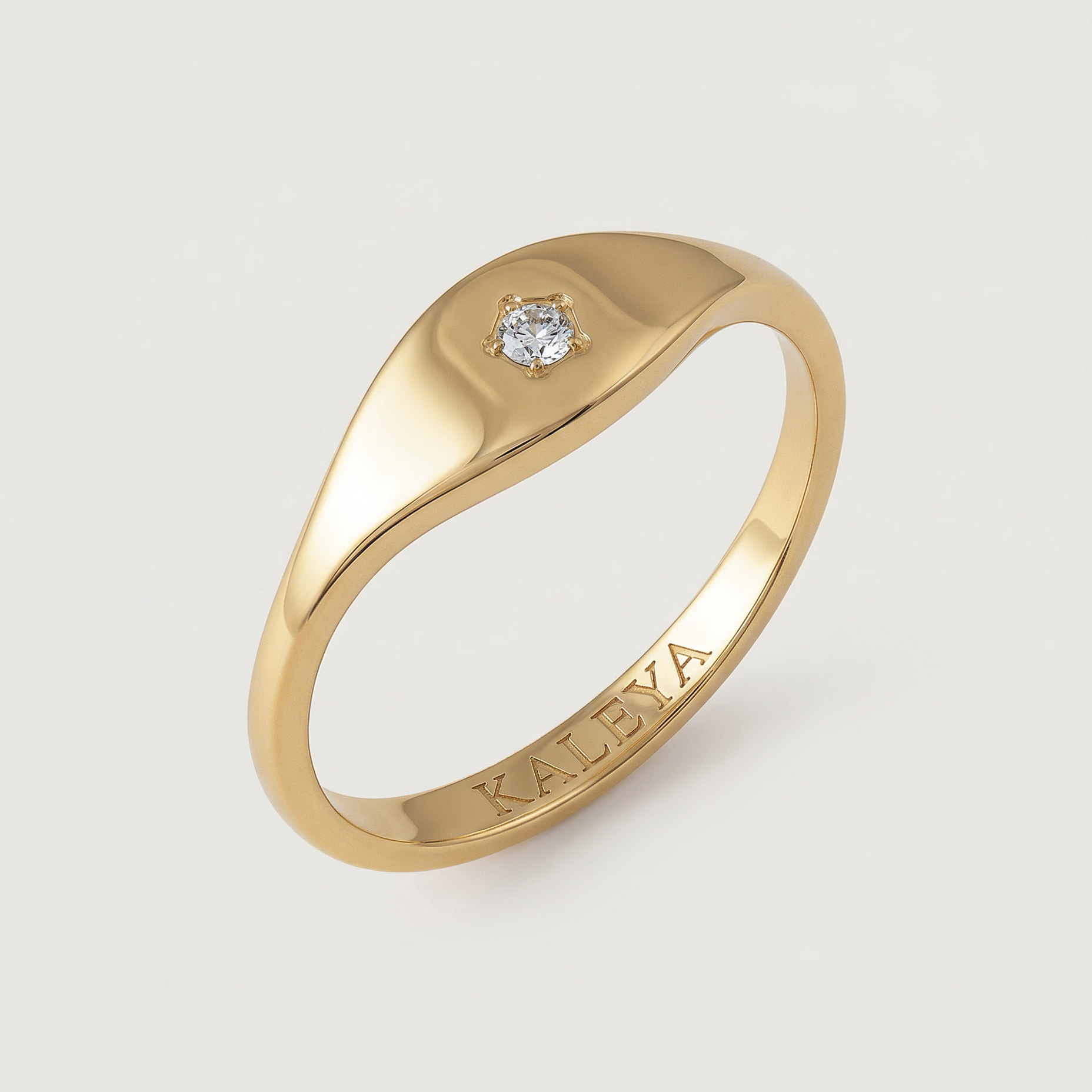 A gold signet ring with a small star-set crystal on the top, displayed against a white background.