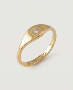 A gold signet ring with a small star-set crystal on the top, displayed against a white background.