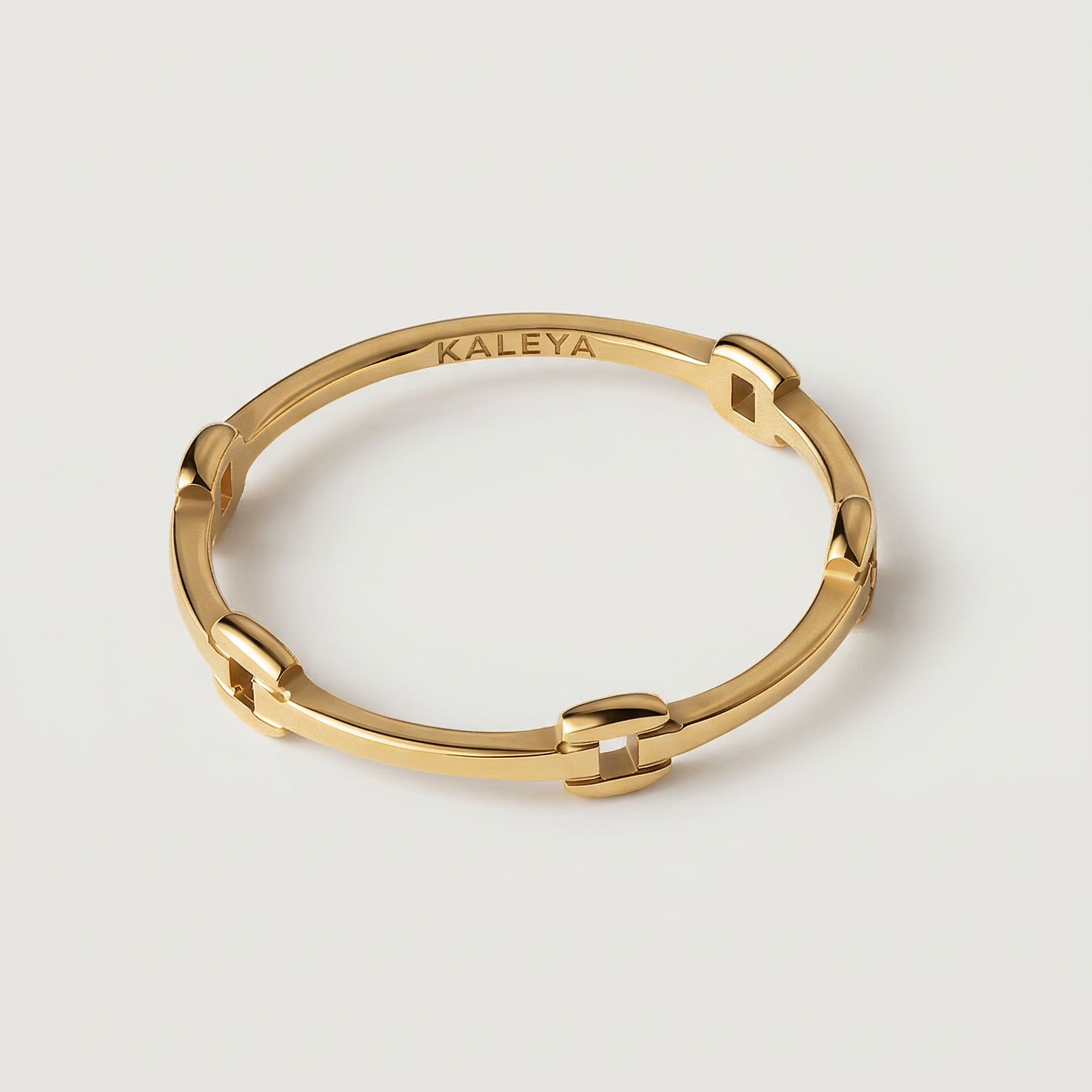 A gold-colored ring with geometric cutouts, crafted from gold-plated metal, displayed against a white background.