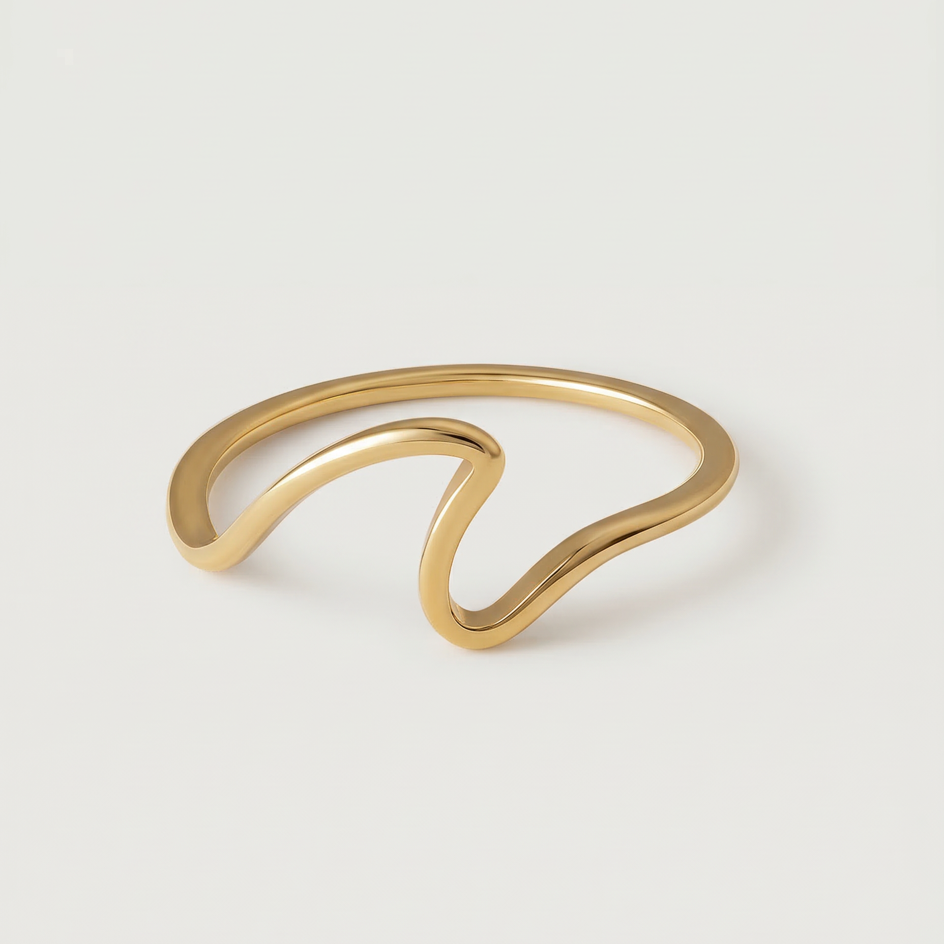 A gold-plated open wave ring on a white background.