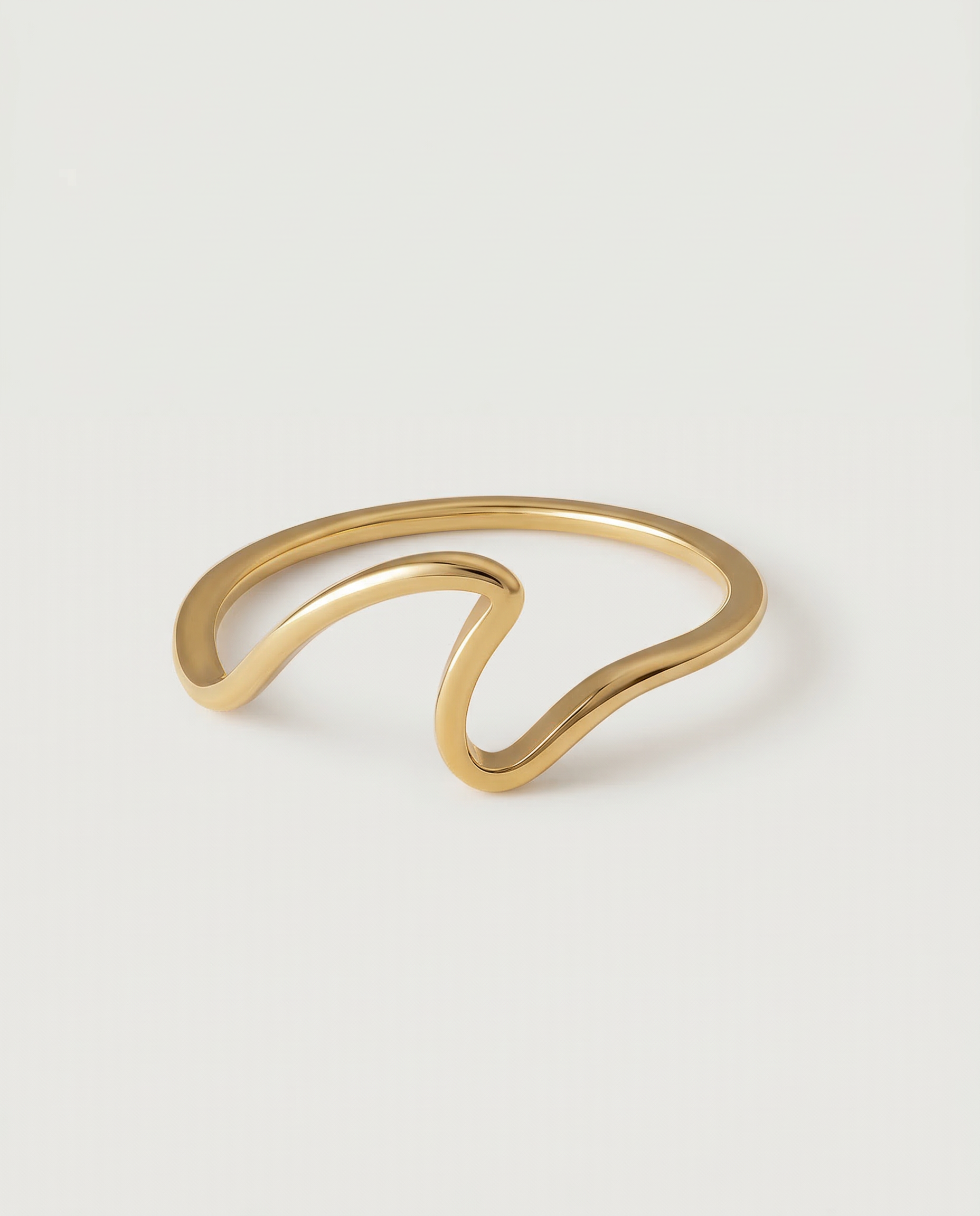 A gold-plated open wave ring on a white background.