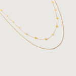 A two-tone necklace with gold links and yellow stones, displayed against a white background