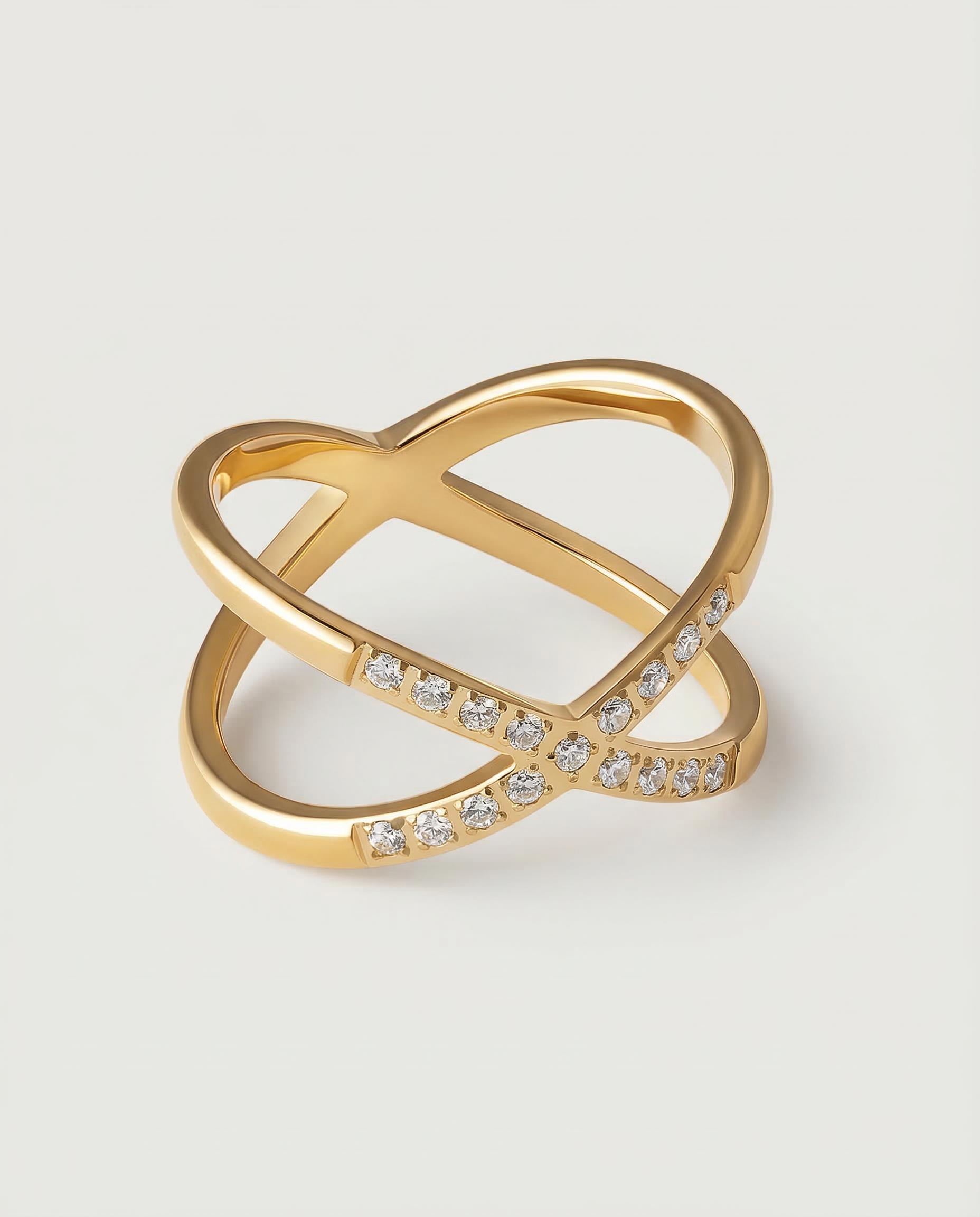 A gold ring with two intersecting bands and small stones set along one band.