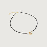 A gold-plated choker necklace with black beads and a crystal-embellished evil eye pendant, featuring an adjustable gold chain.