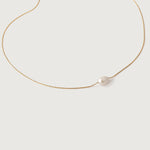 A single white pearl pendant on a thin gold chain, presented against a white background.