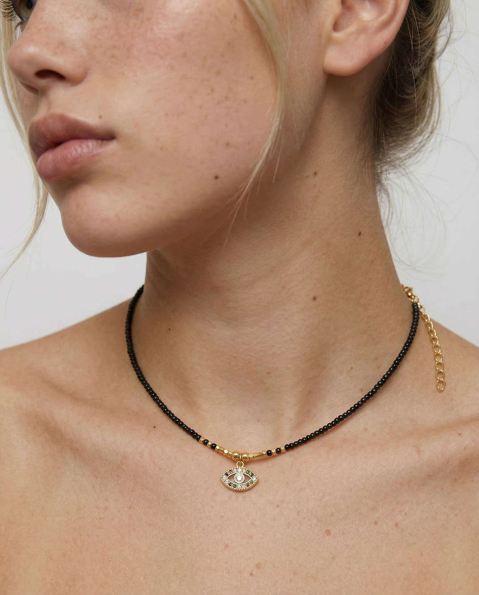 model wearing a gold-plated choker necklace with black beads and a crystal-embellished evil eye pendant