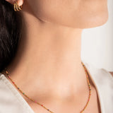 close up of a model wearing a gold-plated necklace with multicolored beads and gold bars
