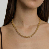 model wearing a gold-plated mesh necklace with a fluid ribbon design