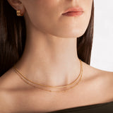 close up of a female model wearing a layered choker necklace with one sleek snake chain and another with tiny spherical stations, both in 18k gold plating.