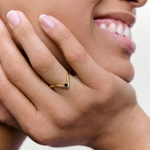 closeup of a model wearing a gold-plated ring with an angular design and a black crystal set in a V-formation