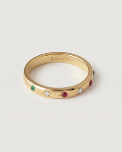 A gold-plated ring with a series of vibrant gemstones set in star-shaped bezels along the polished band.