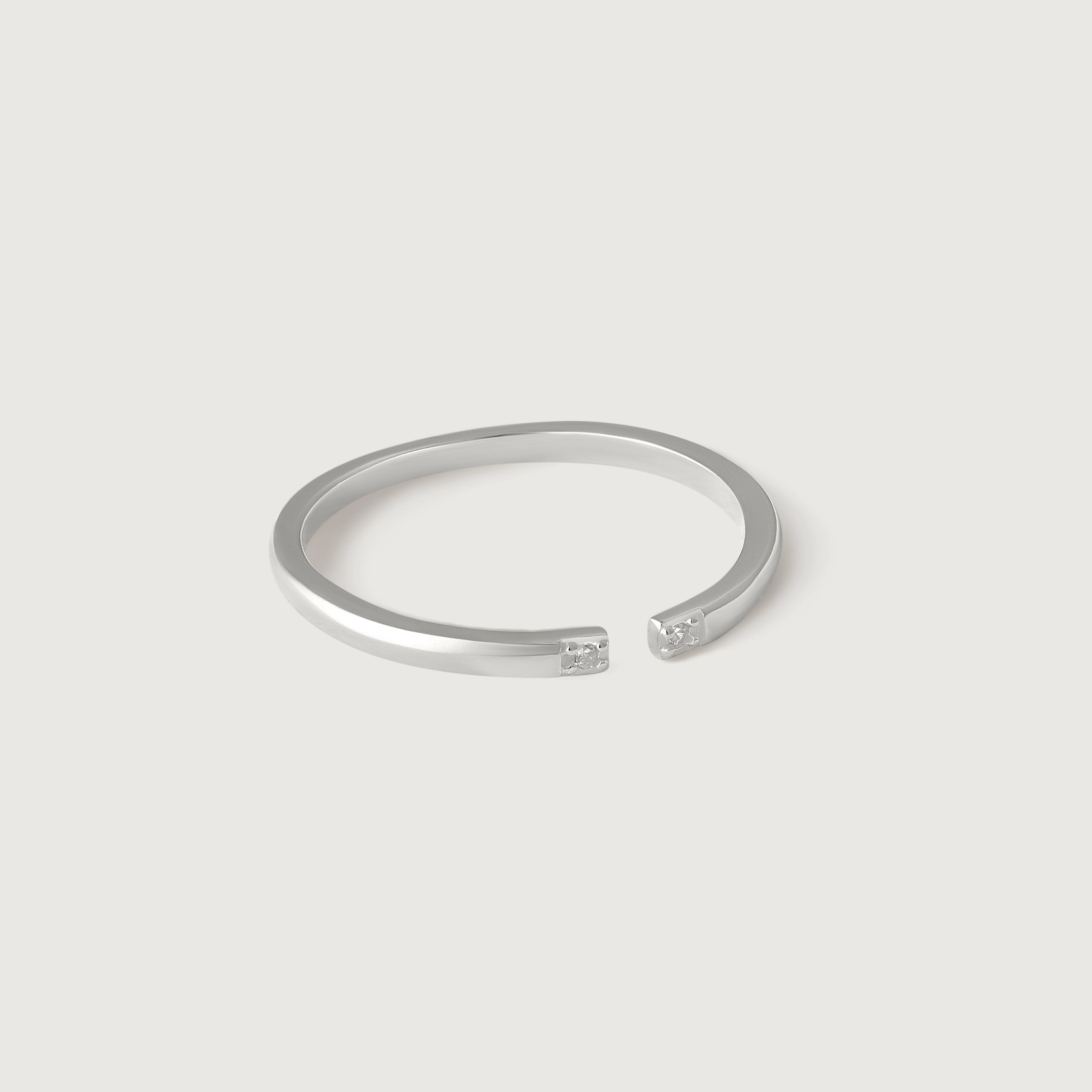 A sterling silver open cuff ring with two tiny CZ stones at each end, displayed against a white background.