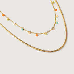 A double-strand necklace with a gold chain and colorful glass beads in orange, green, and yellow hues, alongside a snake chain.