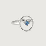 A sleek sterling silver ring with a single blue gemstone in the center, set within a circular frame.