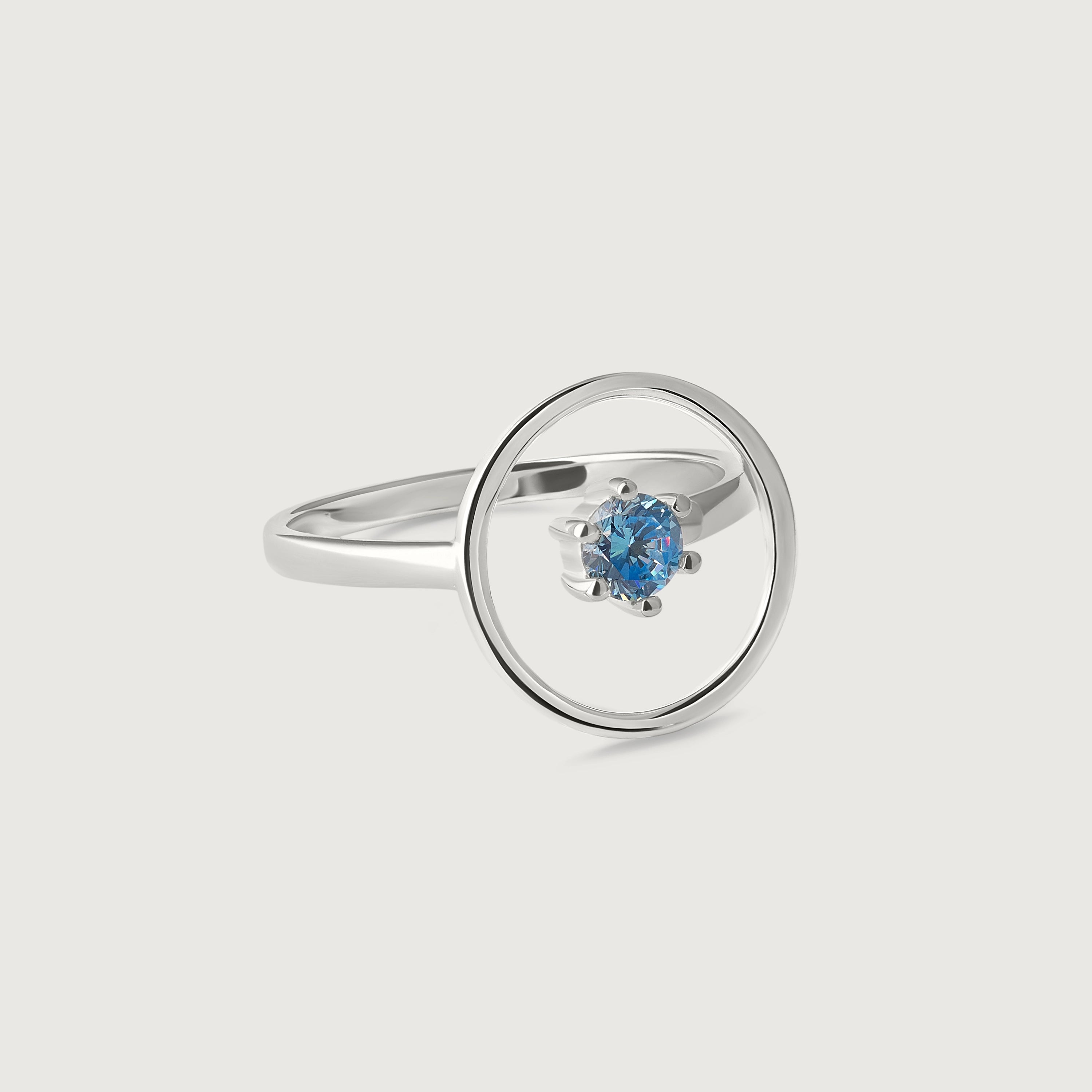 A sleek sterling silver ring with a single blue gemstone in the center, set within a circular frame.