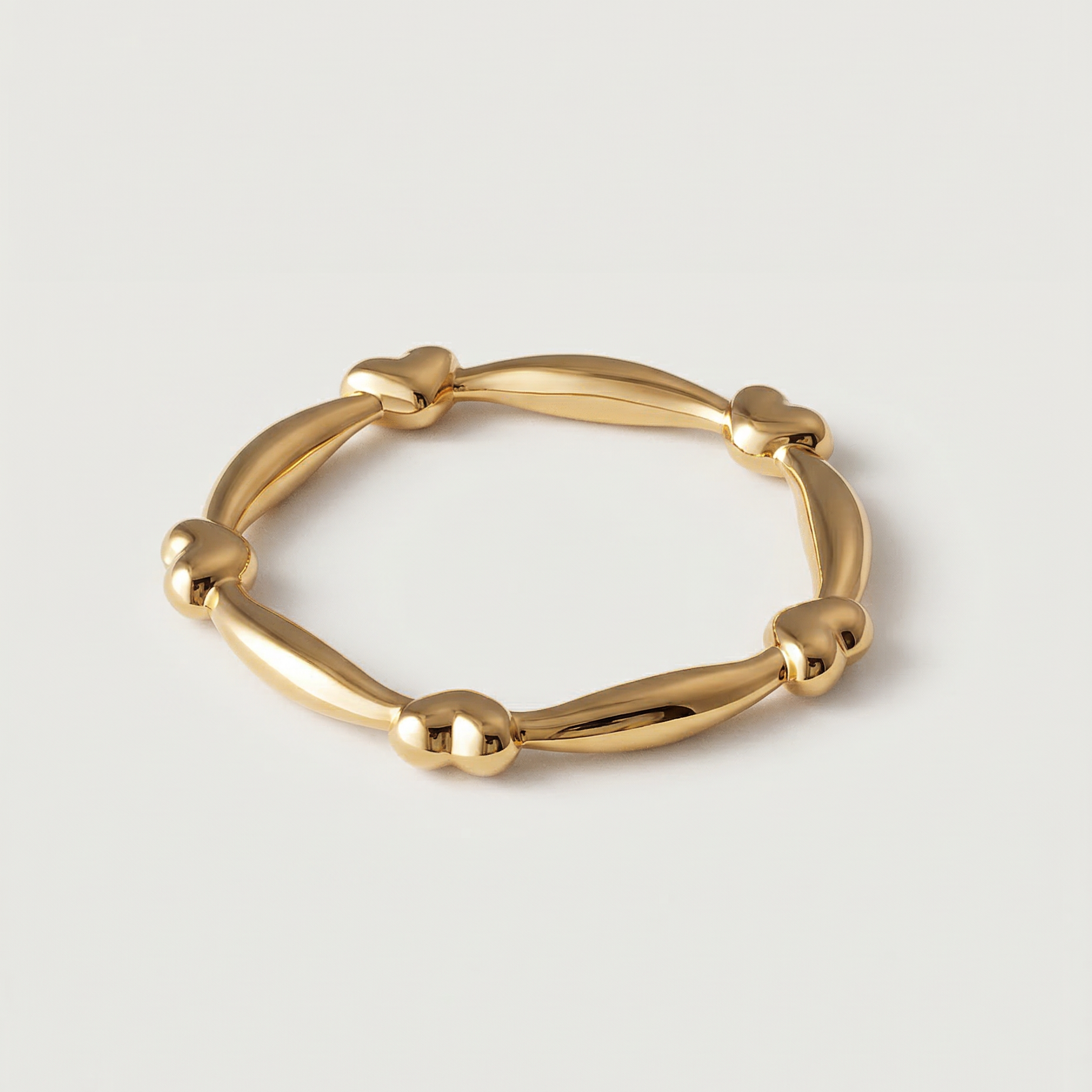 A gold-plated ring with heart-shaped links and elongated bars creating a chain-like design.