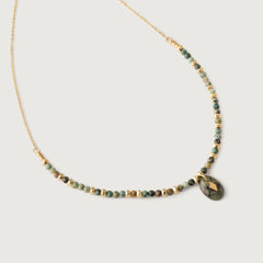A gold-toned necklace with natural African turquoise beads in shades of sage, moss, and earth tones, featuring a smooth oval pendant.