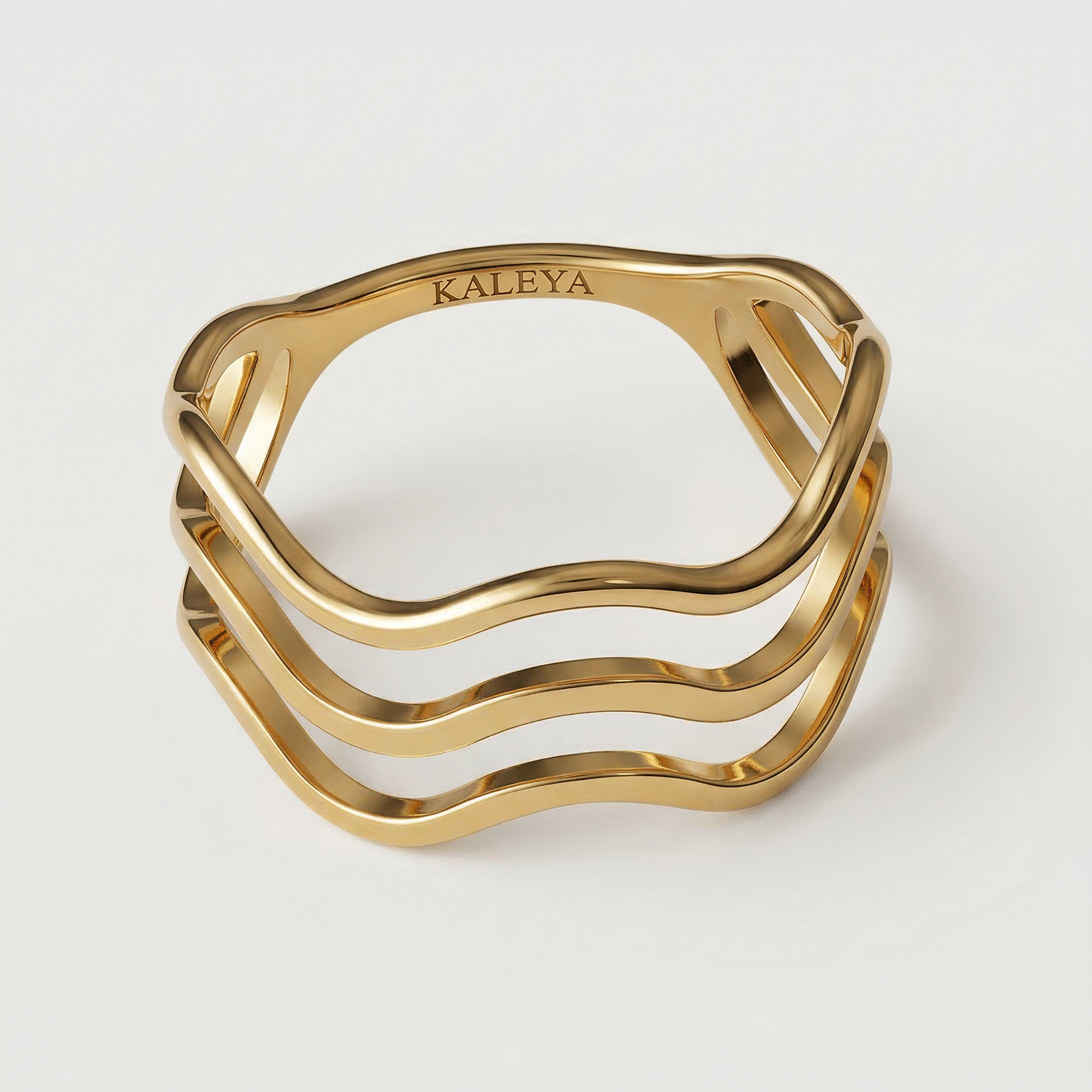 A gold-plated ring with a wave design open band, showing four curved bands that create a sense of lightness and movement.