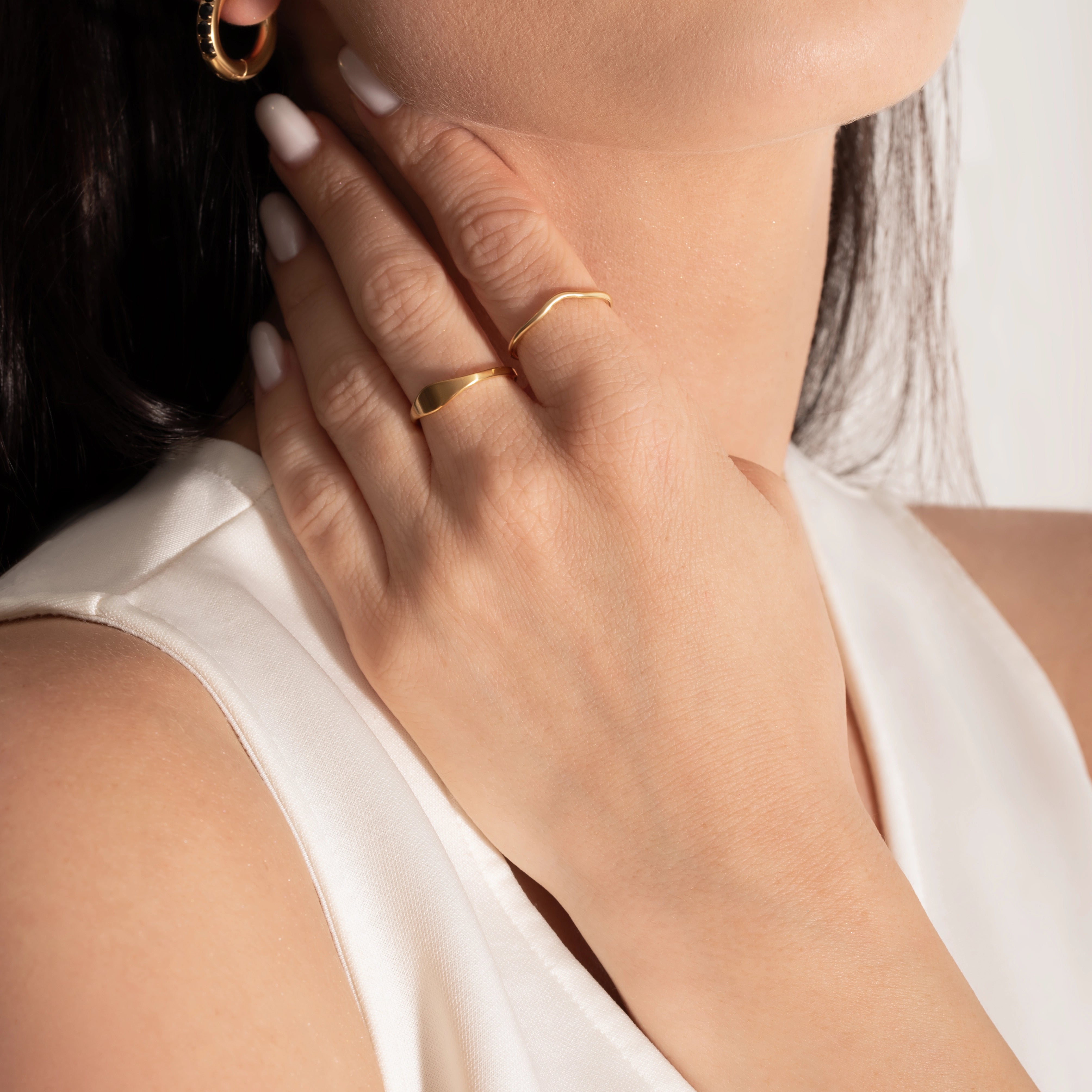 female model wearing a signet ring and a delicate band ring