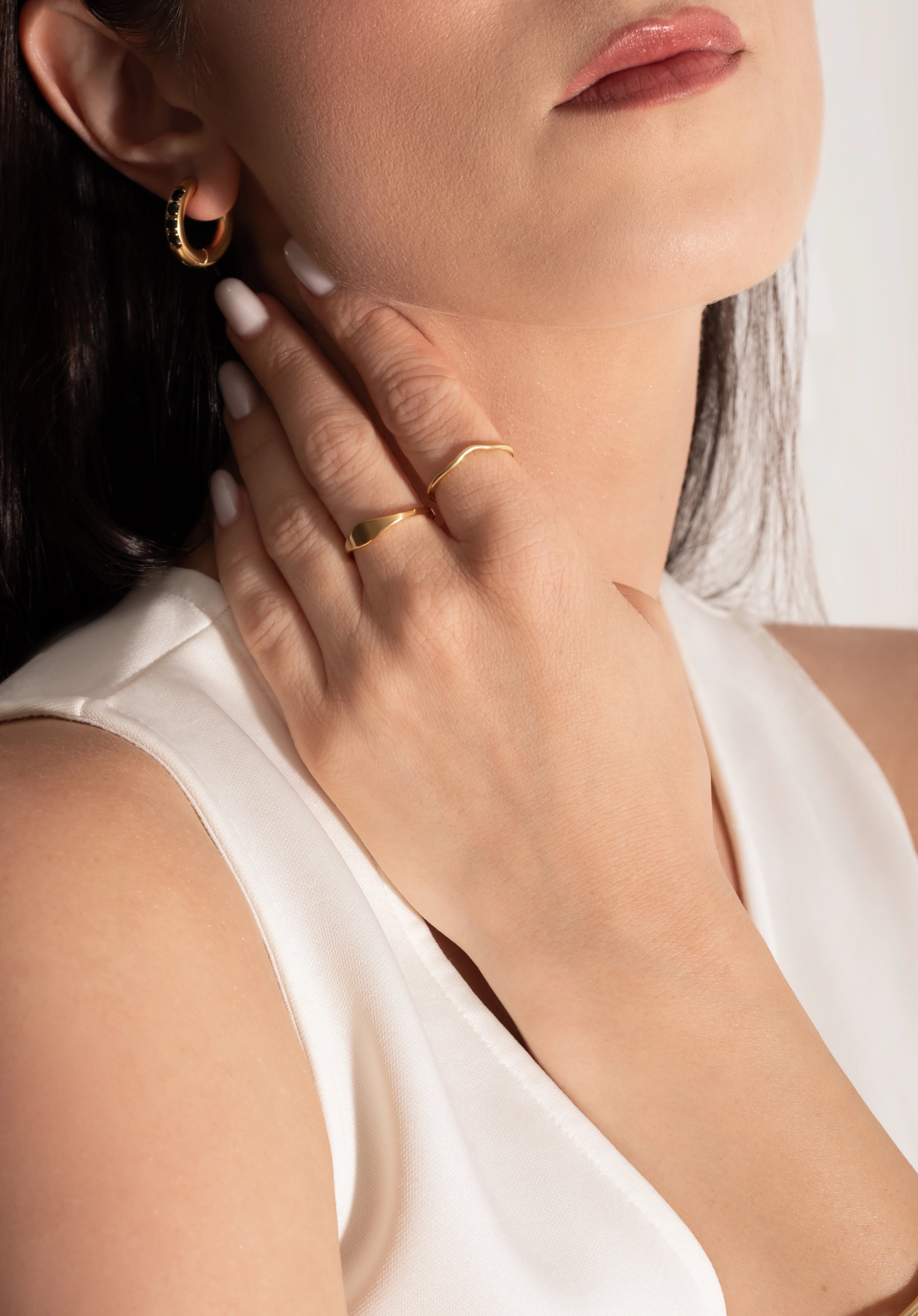 female model wearing a signet ring and a delicate band ring