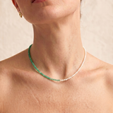 close up of a female model wearing a green aventurine and pearl beaded necklace in gold, with one half strung with pearls and the other half with faceted green aventurine beads in fresh green tones.