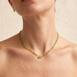 Model wearing the Olive green beaded necklace, the faceted green strand sitting close to the collarbone with the gold and silver ball pendants resting at the centre-front.