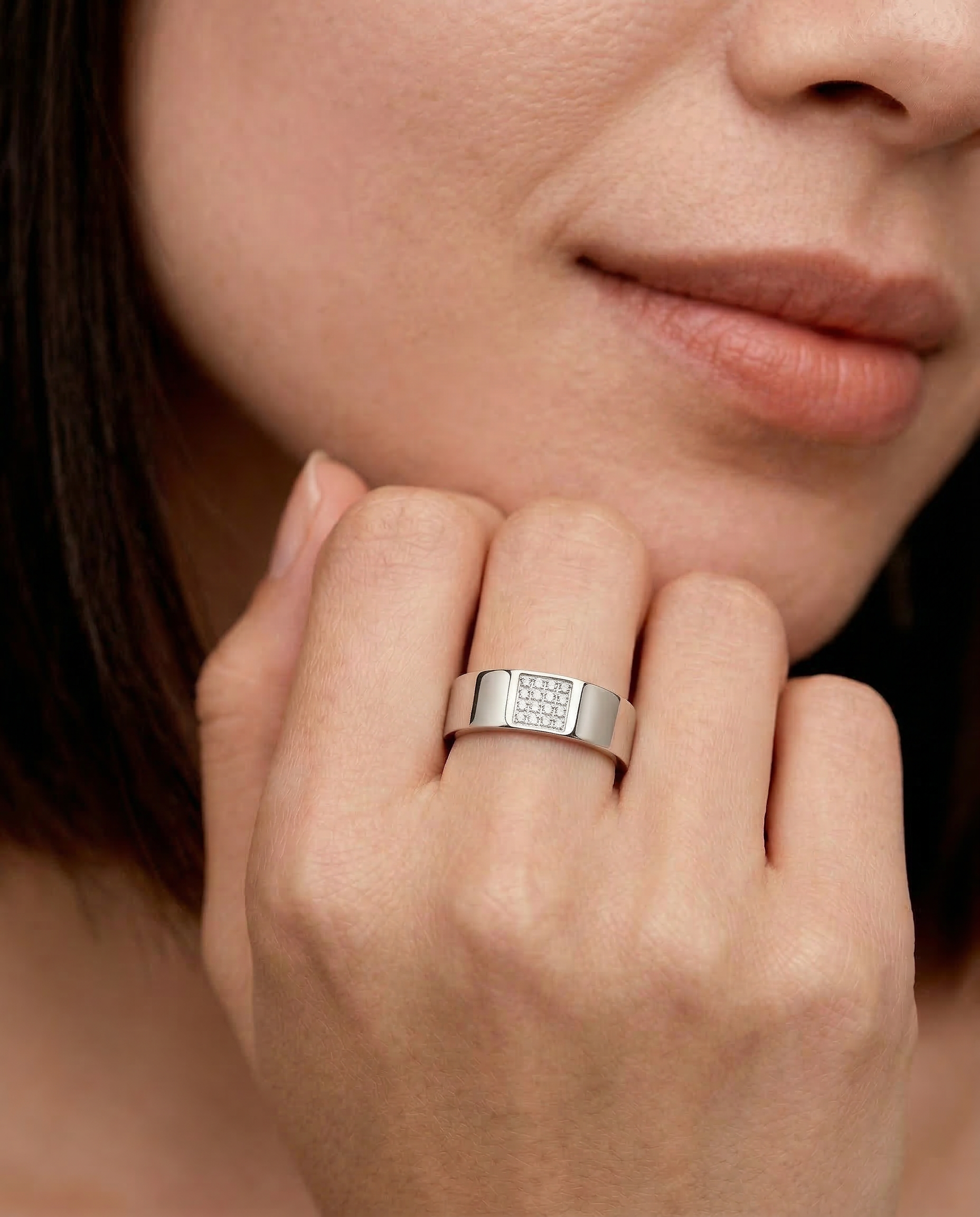 Close-up of a hand wearing A silver ring with a rectangular accent paved with sparkling cubic zirconia stones