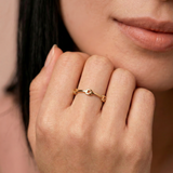 model wearing a gold-colored ring with geometric cutouts, crafted from gold-plated metal, displayed against a white background.