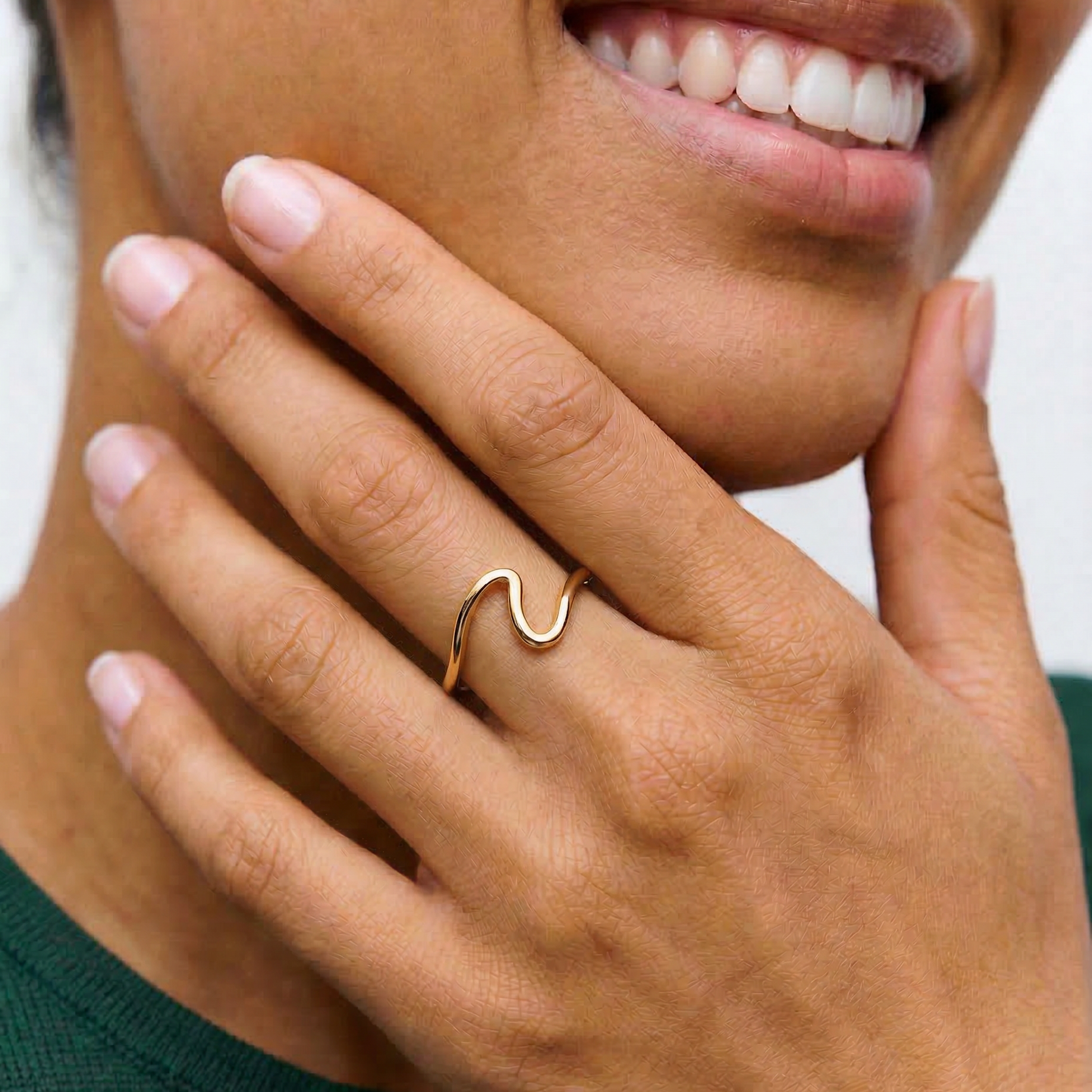 a close up of a model wearing a gold-plated open wave ring