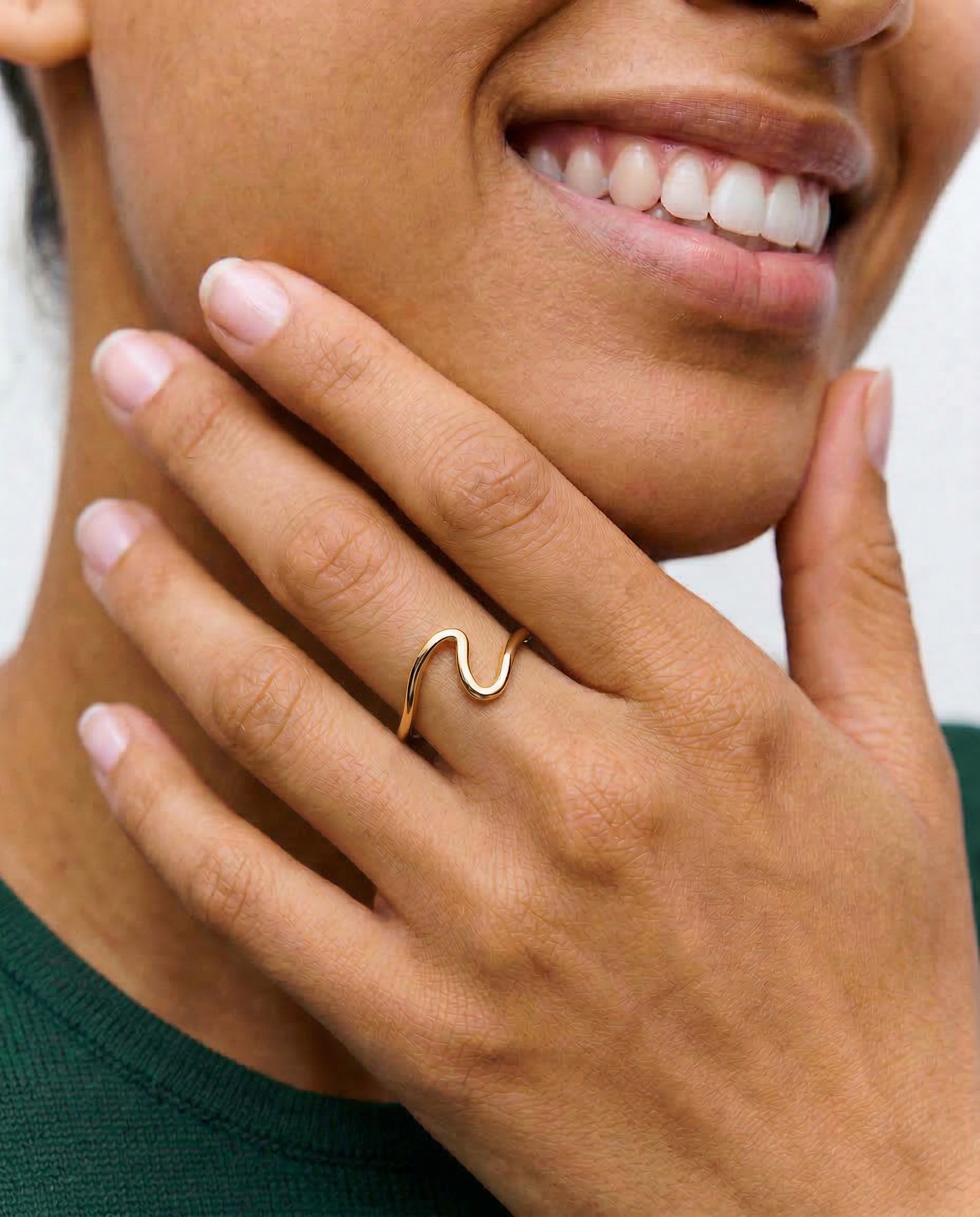 a close up of a model wearing a gold-plated open wave ring