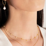 model wearing a delicate two-tone necklace with gold links and yellow stones