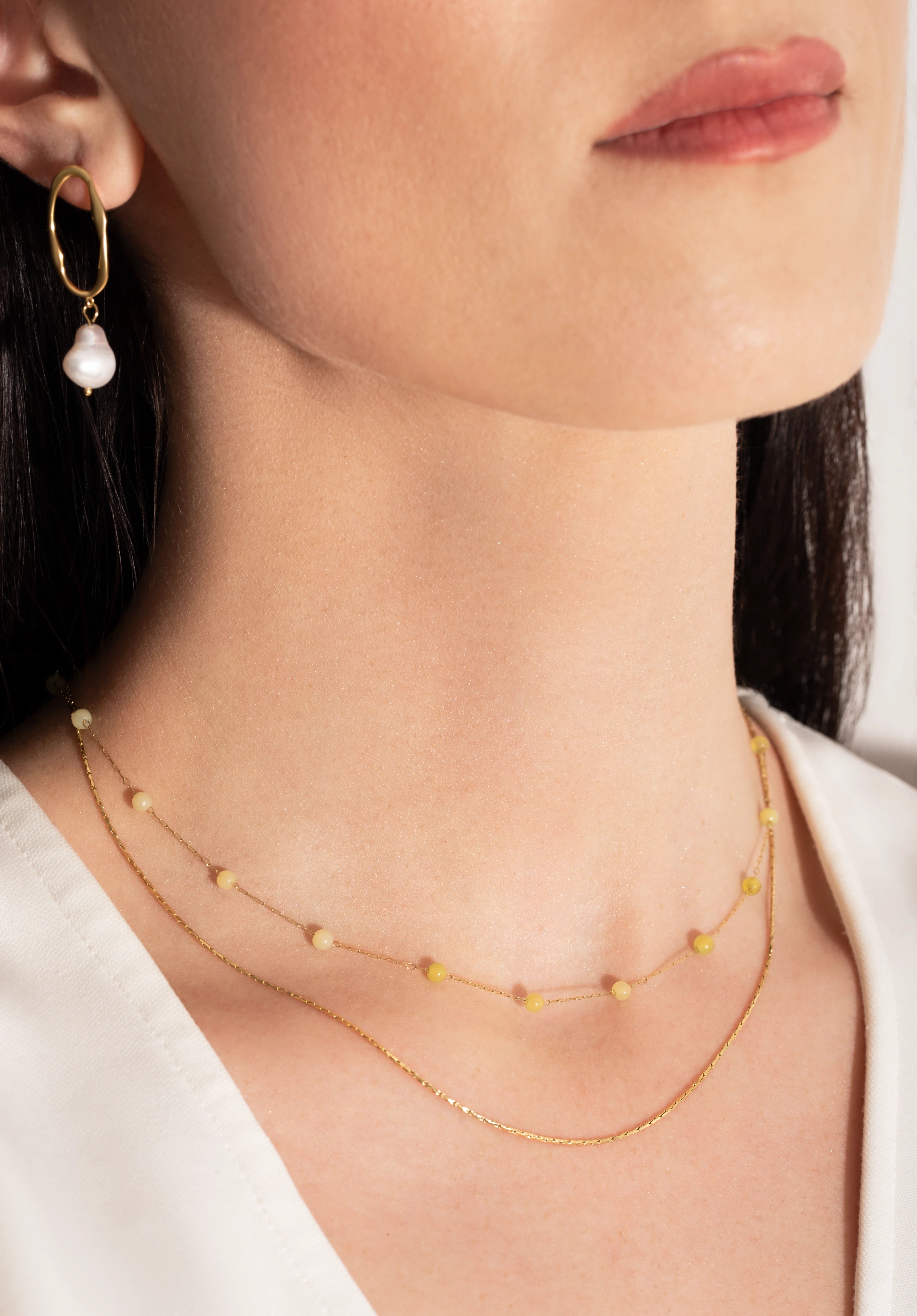 model wearing a delicate two-tone necklace with gold links and yellow stones