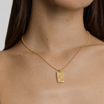 Gold necklace with a rectangular pendant worn by a person