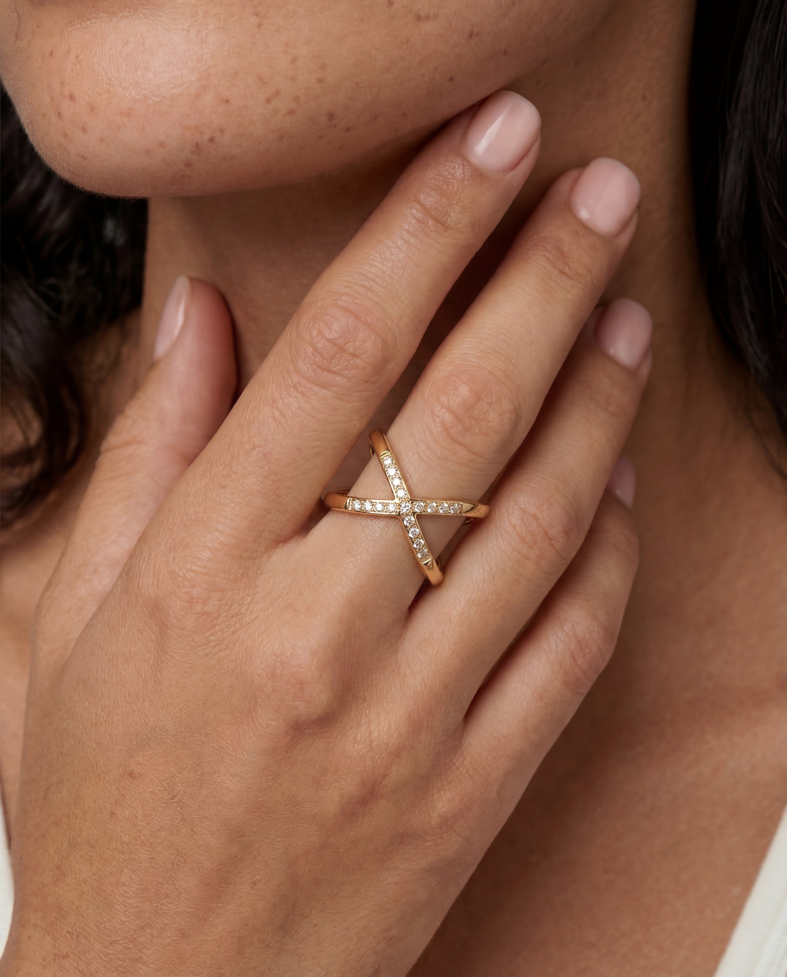 Close-up of a hand wearing a diamond ring with a neutral background