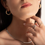 close up of a model wearing two gold and silver rings with two intersecting bands and small stones set along one band