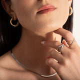 close up of a model wearing two gold and silver rings with two intersecting bands and small stones set along one band