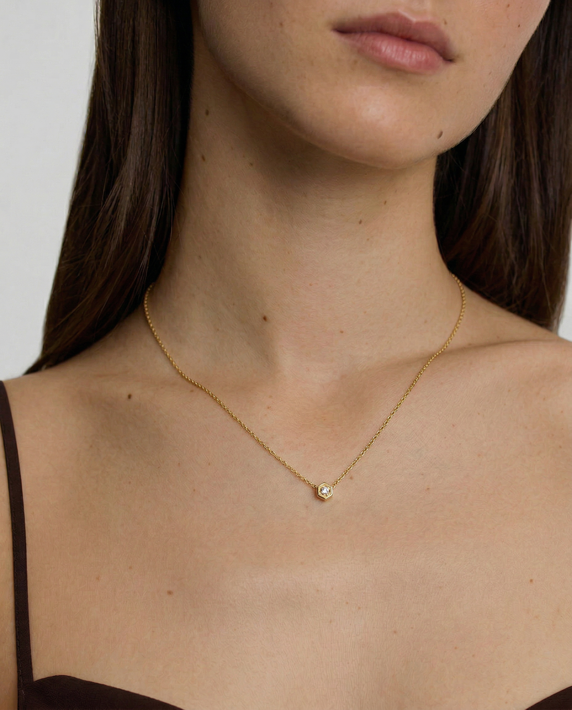 female model wearing a gold necklace with a small round pendant 