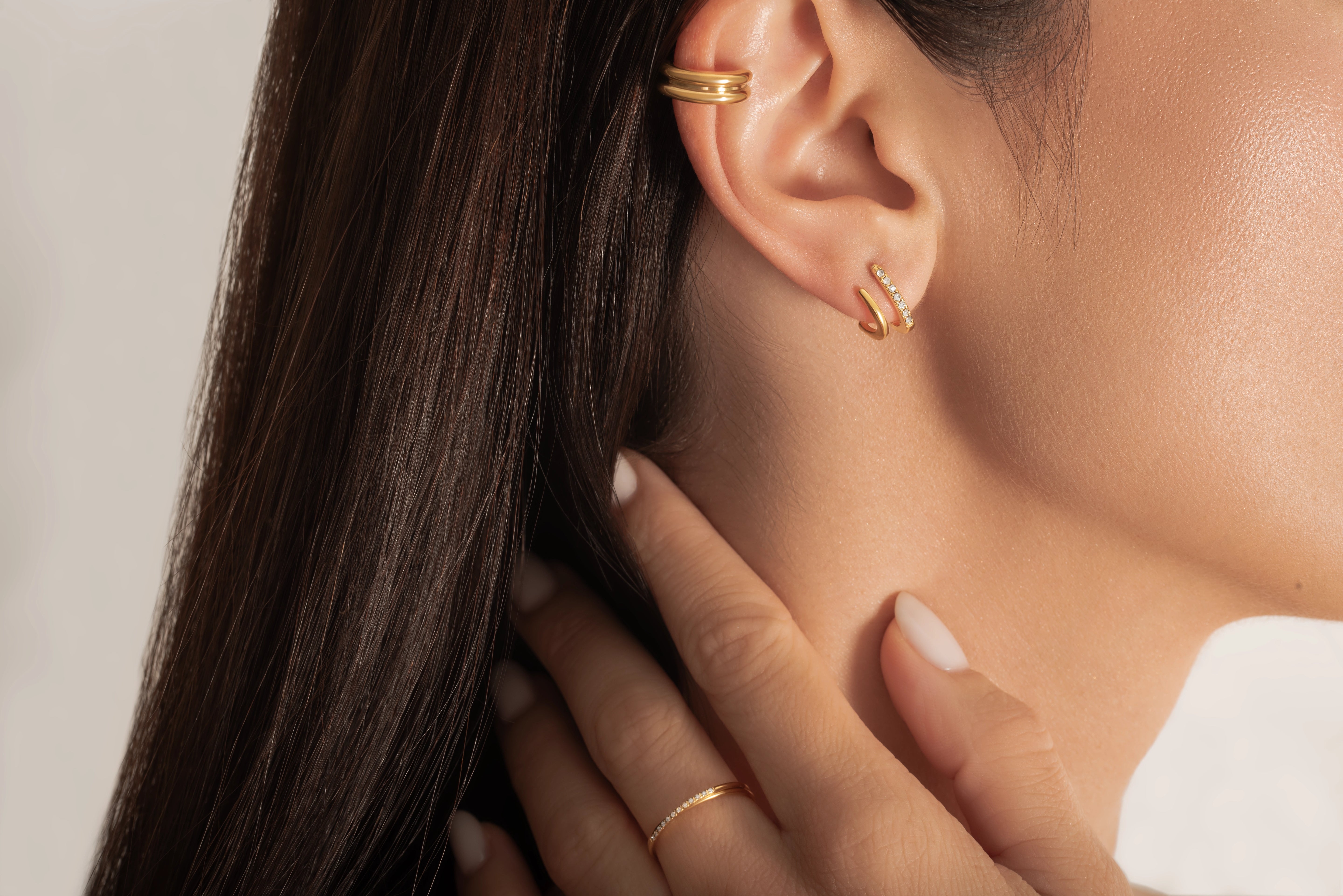 close up of  a model wearing gold plated ring and earrings
