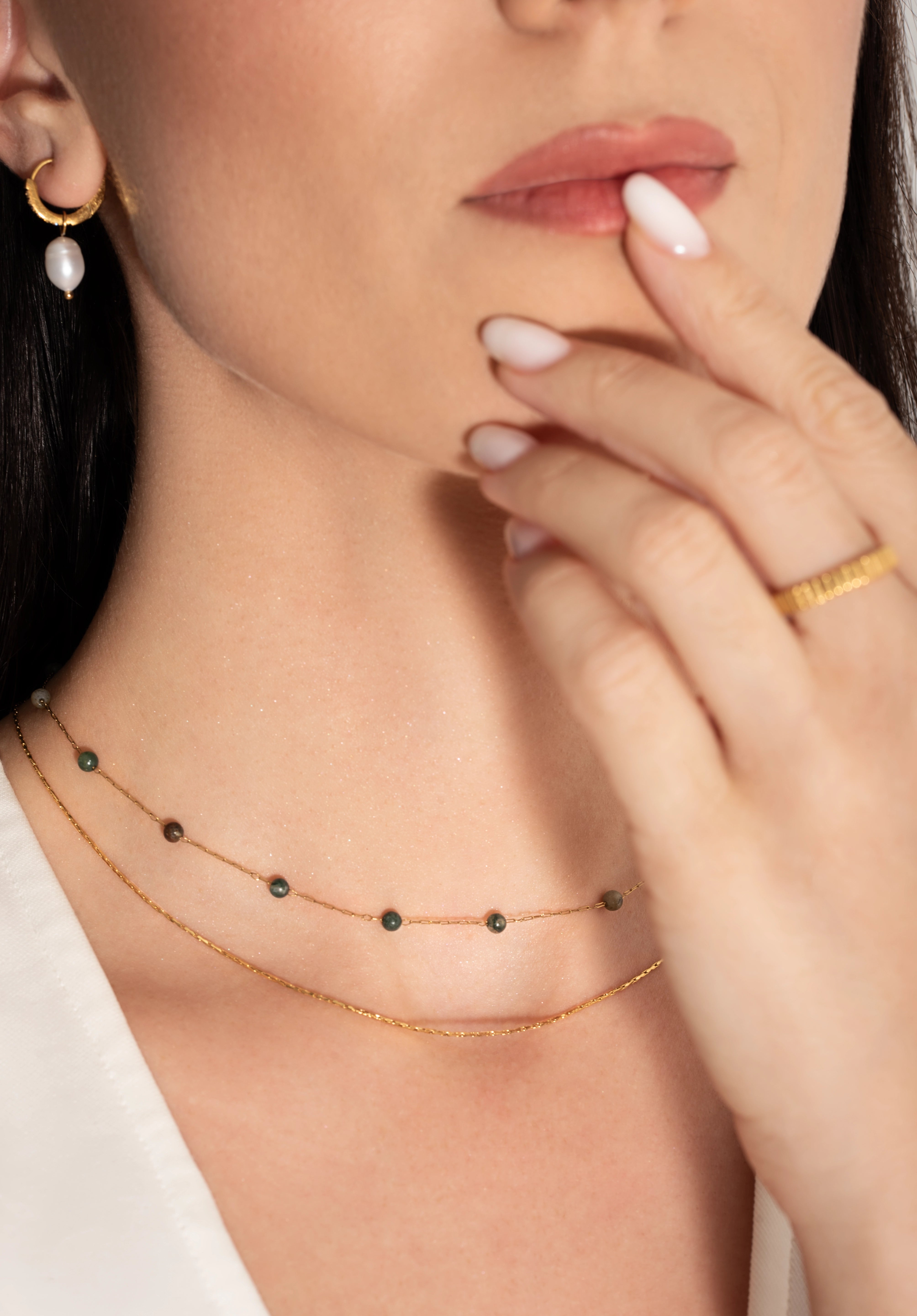 model wearing a two-tiered necklace with fine gold chains and forest-hued jasper beads,
