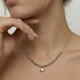 model wearing a gold-plated necklace with sage-green faceted crystals and cubic zirconia charm.