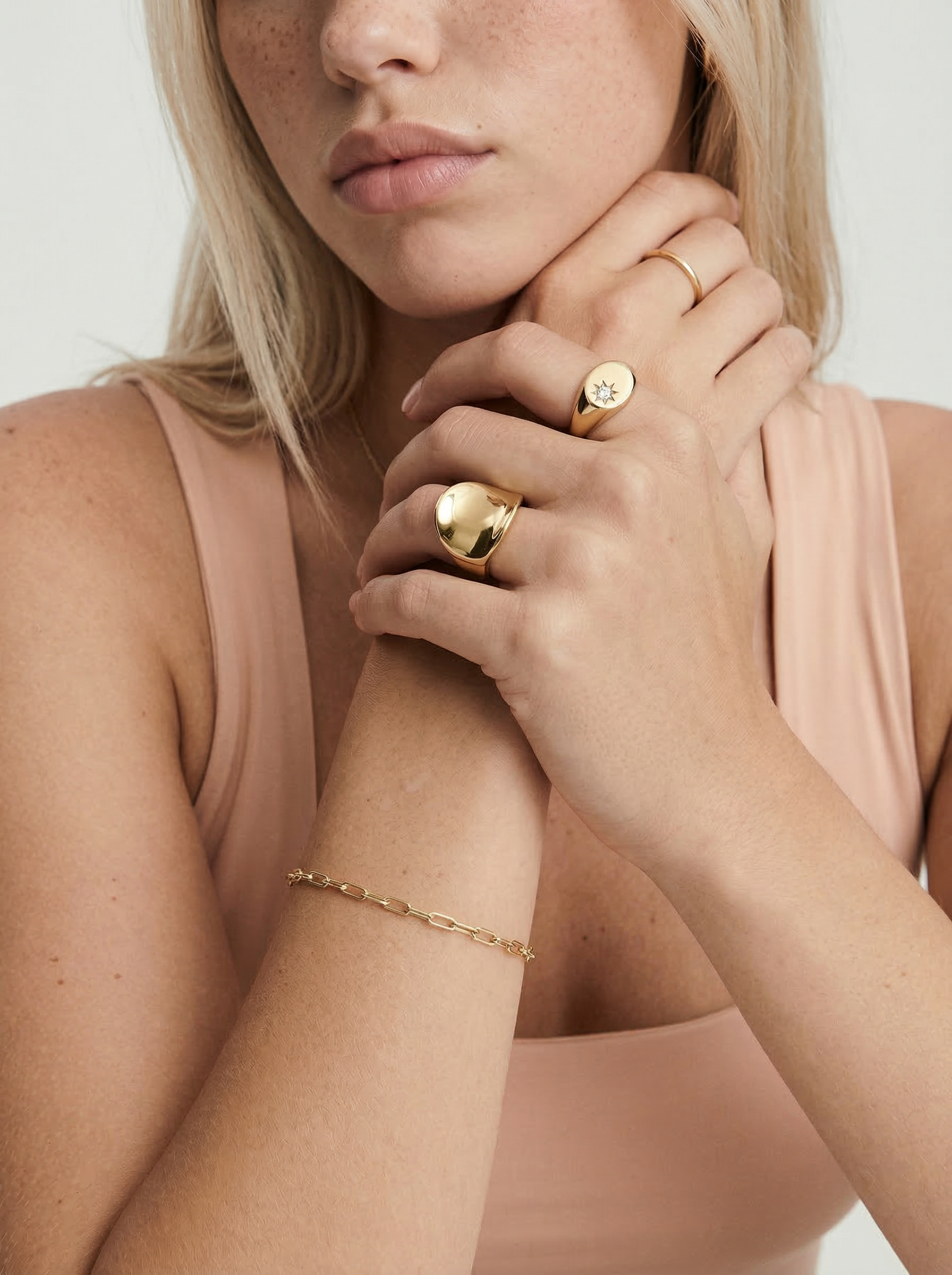 Close-up of a person wearing gold jewelry on a plain background