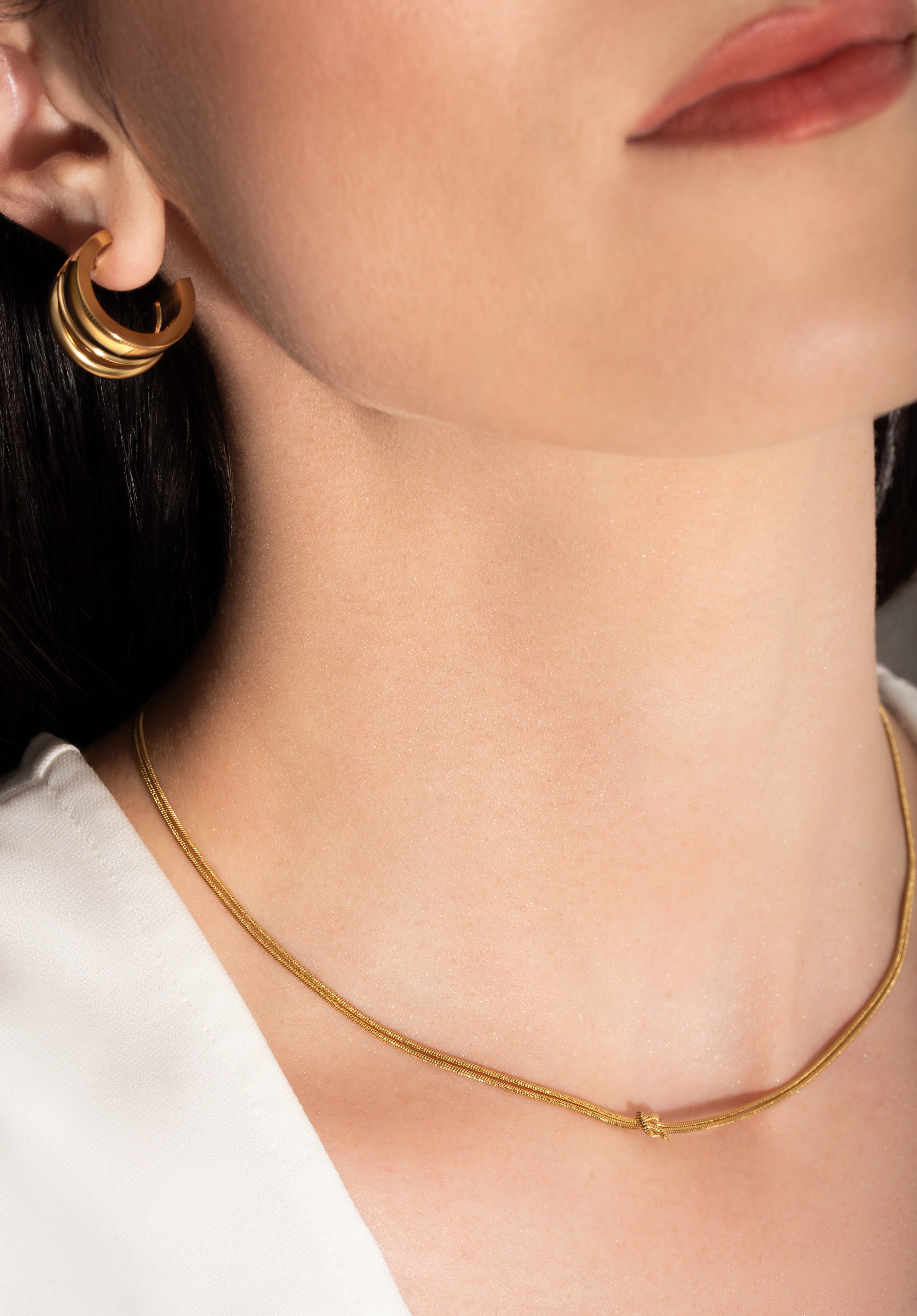 model wearing a gold-plated choker necklace with a simple infinity symbol design