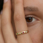 model wearing a gold-plated ring with a series of vibrant gemstones set in star-shaped bezels along the polished band