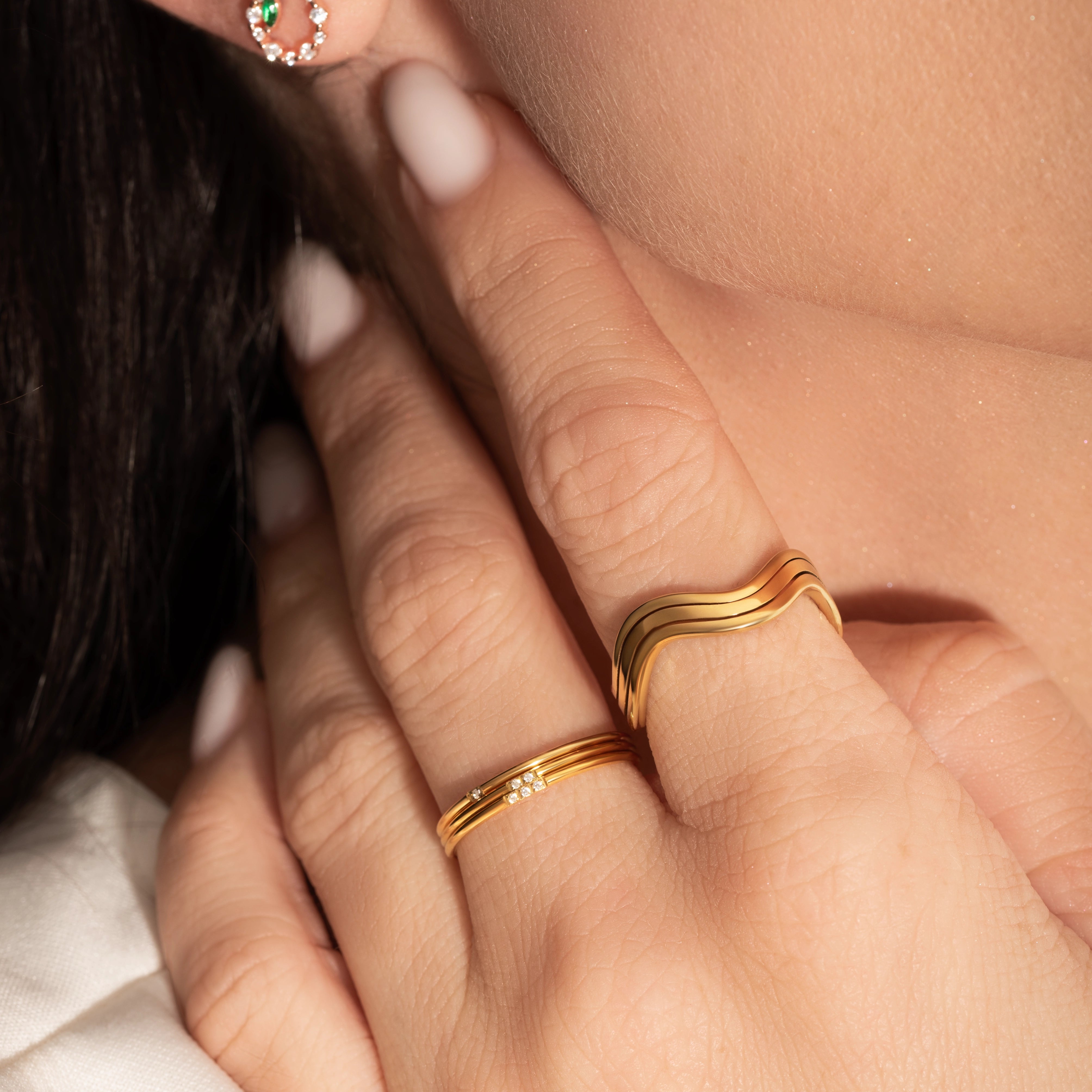 close shot of a model wearing 2 delicate gold rings
