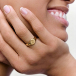 close up of a model wearing a gold signet ring with a star engraving on the top, crafted from gold-plated metal.